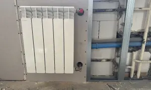 Nowy, biały grzejnik aluminiowy Fondital zamontowany na ścianie z płyty gipsowo-kartonowej. Trwa wymiana grzejnika żeliwnego na aluminiowy.