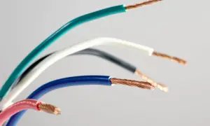 Różne kolory przewodów elektrycznych: zielony, biały, czarny, niebieski i różowy, z odsłoniętymi miedzianymi żyłami.
