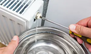 Woda kapie z odpowietrznika grzejnika, gdy próbuje się rozwiązać problem, dlaczego grzejnik nie grzeje mimo odpowietrzenia.