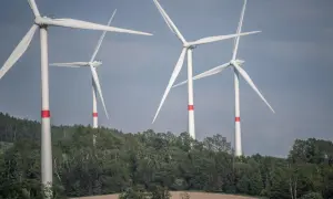 Wiatraki na tle zielonych wzgórz. Zastanawiasz się, ile wiatrak produkuje energii dziennie?