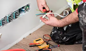 Elektryk przygotowuje przewody do podłączenia gniazdek. To faza prac remontowych.