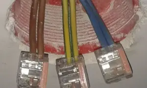 Trzy przewody elektryczne (brązowy, żółto-zielony, niebieski) połączone w puszkach. Czy faza to plus czy minus?