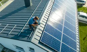 Technik sprawdza instalację, pokazując, jak podłączyć panele fotowoltaiczne na dachu.