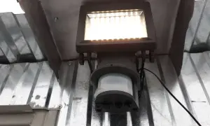Lampa z czujnikiem ruchu sama się zapala, bo wykrywa ruch. Jasne światło oświetla metalową konstrukcję.
