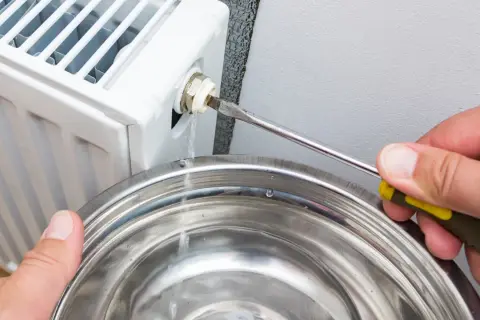 Woda kapie z odpowietrznika grzejnika, gdy próbuje się rozwiązać problem, dlaczego grzejnik nie grzeje mimo odpowietrzenia.