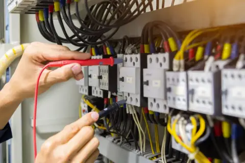 Elektryk sprawdza połączenia w szafie sterowniczej, badając, skąd się bierze przewód neutralny.