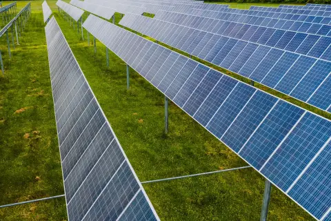 Rzędy paneli fotowoltaicznych na zielonej łące. To idealne miejsce na depozyt prosumencki, księgowanie energii odnawialnej.