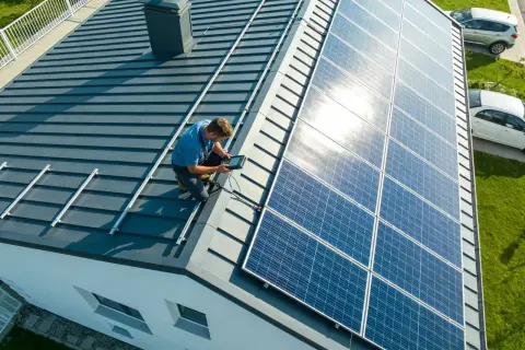 Technik sprawdza instalację, pokazując, jak podłączyć panele fotowoltaiczne na dachu.