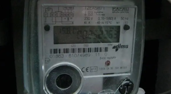 Cyfrowy licznik energii elektrycznej z widoczną czerwoną lampką w liczniku prądu, migającą podczas pracy.