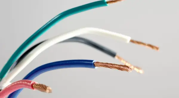 Różne kolory przewodów elektrycznych: zielony, biały, czarny, niebieski i różowy, z odsłoniętymi miedzianymi żyłami.