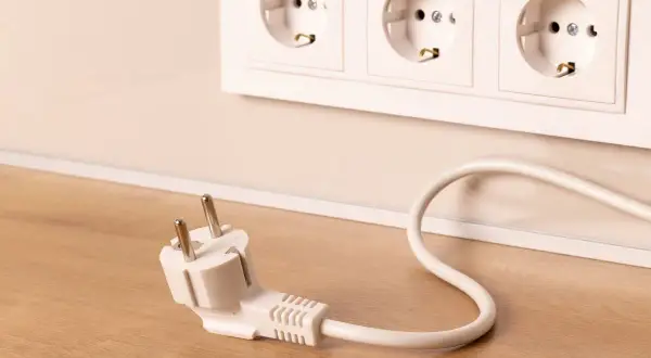 Wtyczka leży obok gniazdek elektrycznych. Zastanawiasz się, jakie powinno być napięcie w sieci, by wszystko działało bezpiecznie?