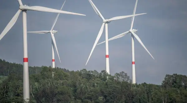 Wiatraki na tle zielonych wzgórz. Zastanawiasz się, ile wiatrak produkuje energii dziennie?