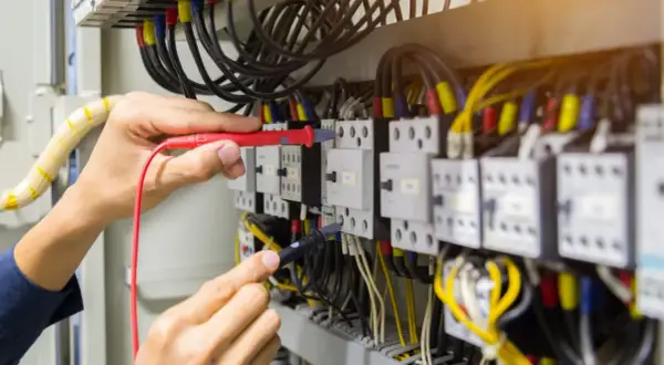 Elektryk sprawdza połączenia w szafie sterowniczej, badając, skąd się bierze przewód neutralny.