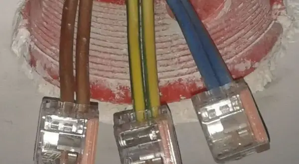 Trzy przewody elektryczne (brązowy, żółto-zielony, niebieski) połączone w puszkach. Czy faza to plus czy minus?