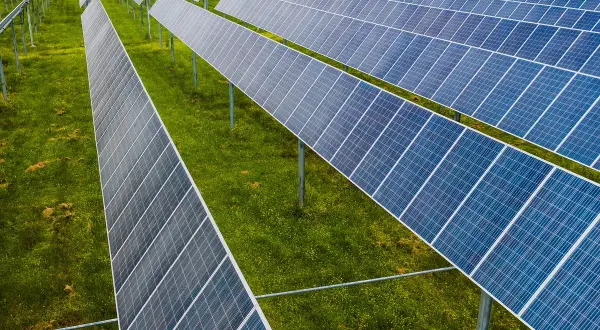 Rzędy paneli fotowoltaicznych na zielonej łące. To idealne miejsce na depozyt prosumencki, księgowanie energii odnawialnej.
