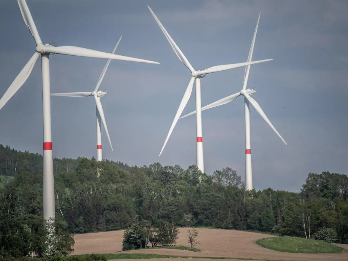 Wiatraki na tle zielonych wzgórz. Zastanawiasz się, ile wiatrak produkuje energii dziennie?