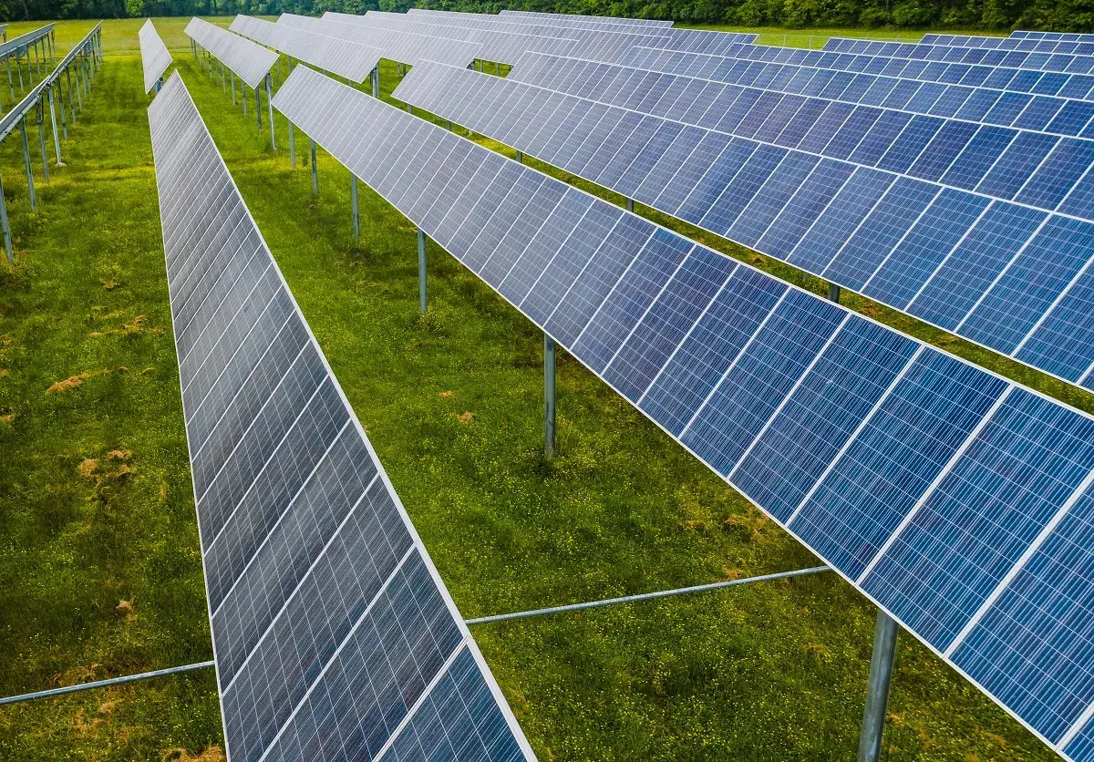Rzędy paneli fotowoltaicznych na zielonej łące. To idealne miejsce na depozyt prosumencki, księgowanie energii odnawialnej.
