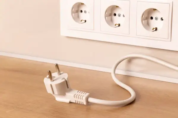 Wtyczka leży obok gniazdek elektrycznych. Zastanawiasz się, jakie powinno być napięcie w sieci, by wszystko działało bezpiecznie?
