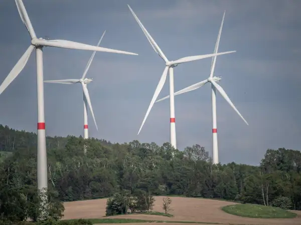 Wiatraki na tle zielonych wzgórz. Zastanawiasz się, ile wiatrak produkuje energii dziennie?
