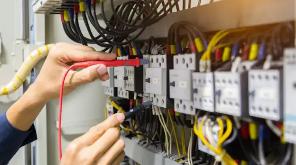 Elektryk sprawdza połączenia w szafie sterowniczej, badając, skąd się bierze przewód neutralny.