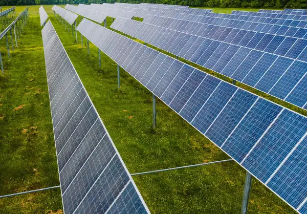 Rzędy paneli fotowoltaicznych na zielonej łące. To idealne miejsce na depozyt prosumencki, księgowanie energii odnawialnej.
