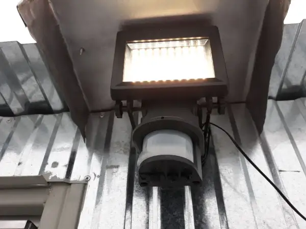 Lampa z czujnikiem ruchu sama się zapala, bo wykrywa ruch. Jasne światło oświetla metalową konstrukcję.